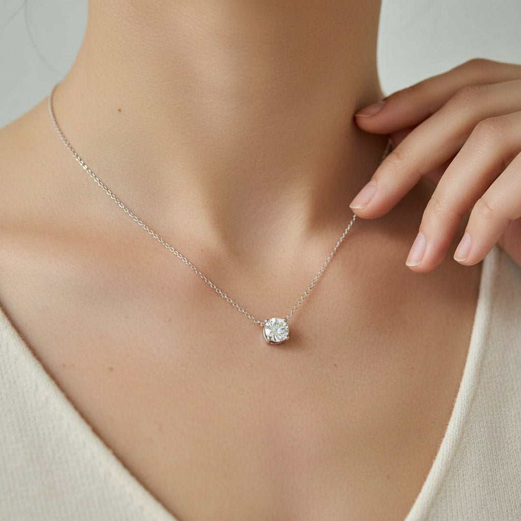 Necklace with a diamond pendant worn by a person, against a neutral background