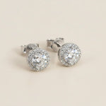 Platinum-plated sterling silver stud earrings featuring round lab-grown moissanite stones with halo detailing.