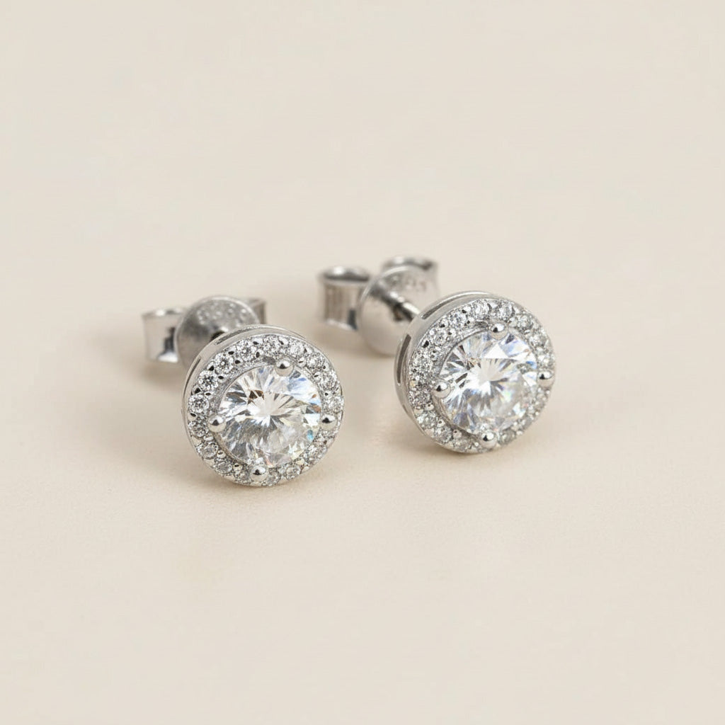 Platinum-plated sterling silver stud earrings featuring round lab-grown moissanite stones with halo detailing.