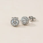 Platinum-plated sterling silver halo stud earrings featuring brilliant round lab-grown moissanite center stones.