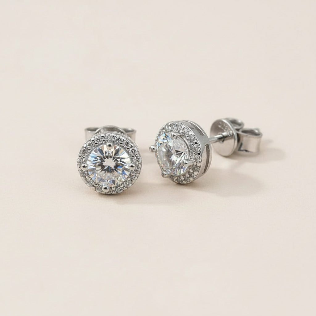 Platinum-plated sterling silver halo stud earrings featuring brilliant round lab-grown moissanite center stones.