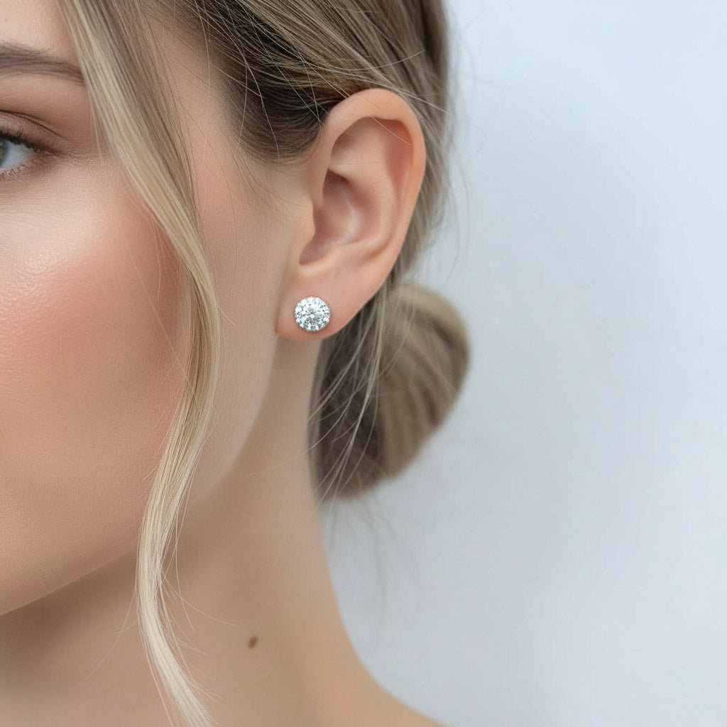 Model wearing platinum-plated sterling silver halo stud earrings with round lab-grown moissanite stones.