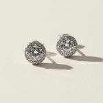 Platinum-plated sterling silver stud earrings with round lab-grown moissanite center stones and halo setting.