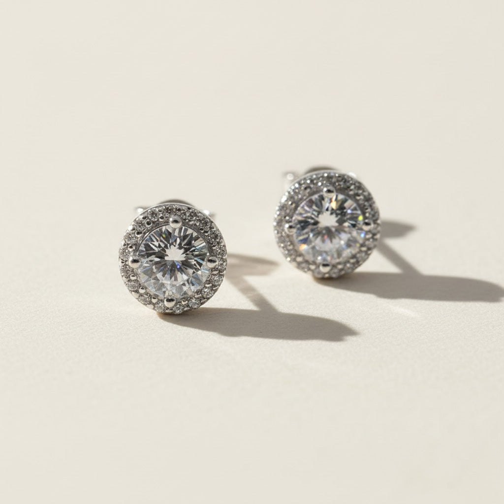 Platinum-plated sterling silver stud earrings with round lab-grown moissanite center stones and halo setting.