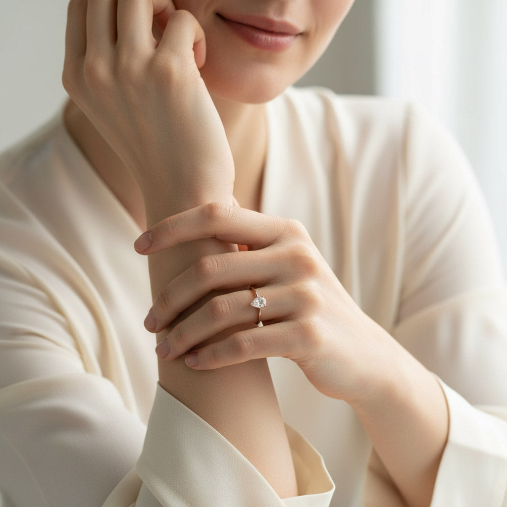 Pear cut moissanite solitaire ring on model’s hand in gold plating