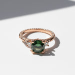 Rose gold ring with 2ct green moissanite and side stones in sunlight