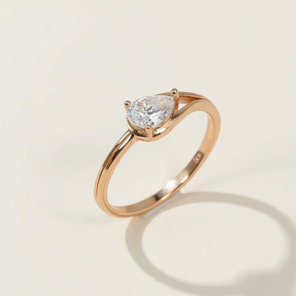 Rose gold-plated sterling silver ring with pear-cut lab grown moissanite solitaire, elegant minimalist design.