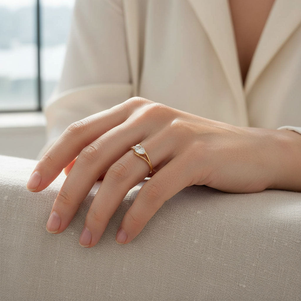 Woman wearing rose gold-plated sterling silver pear-cut moissanite solitaire ring, elegant minimalist design.
