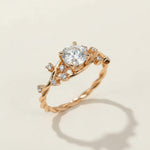 Gold-plated vine-inspired ring with round moissanite center stone and small CZ accents on twisted band by A2K London.