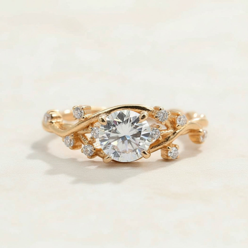 Gold-plated ring with round brilliant moissanite center stone and vine-inspired band set with small CZ accents by A2K London.