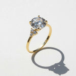 Gold 3ct moissanite ring casting shadow on white surface