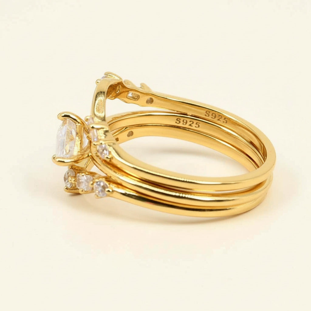 A side view of a set of three gold-plated S925 sterling silver rings. The set features a marquise-cut moissanite center stone and two matching curved bands with round accent stones, showcasing the smooth polished finish and engraved “S925” hallmark inside the bands.