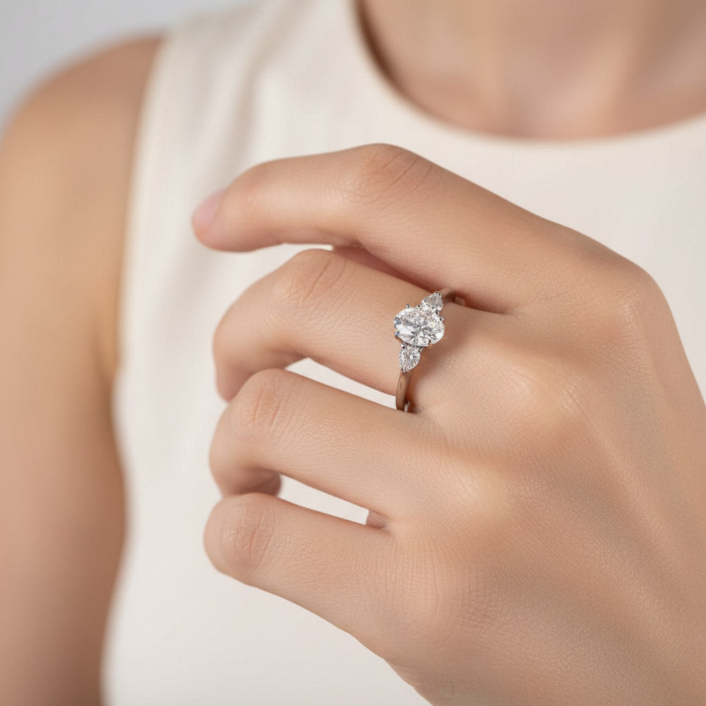 Model wearing 1.5ct oval three-stone moissanite ring in platinum sterling silver.