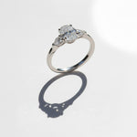 Oval three-stone moissanite ring in platinum silver with shadow detail.