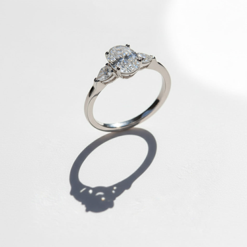 Oval three-stone moissanite ring in platinum silver with shadow detail.