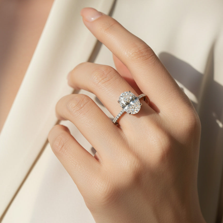 3ct Oval cut lab grown diamond ring worn on finger, pavé band, platinum plated silver