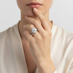 Close-up of a hand wearing a diamond ring with a neutral background