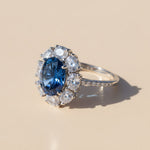 Side angle of sapphire blue oval ring with moissanite halo, platinum plated sterling silver band