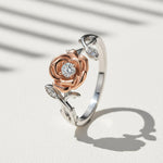 Two-tone rose flower moissanite ring with 0.1ct center stone in platinum and rose gold plated silver on a light background
