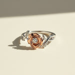 Rose gold flower moissanite ring with platinum plated band in soft sunlight