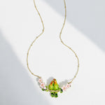 Necklace with a green parrot pendant and pink flowers on a white background