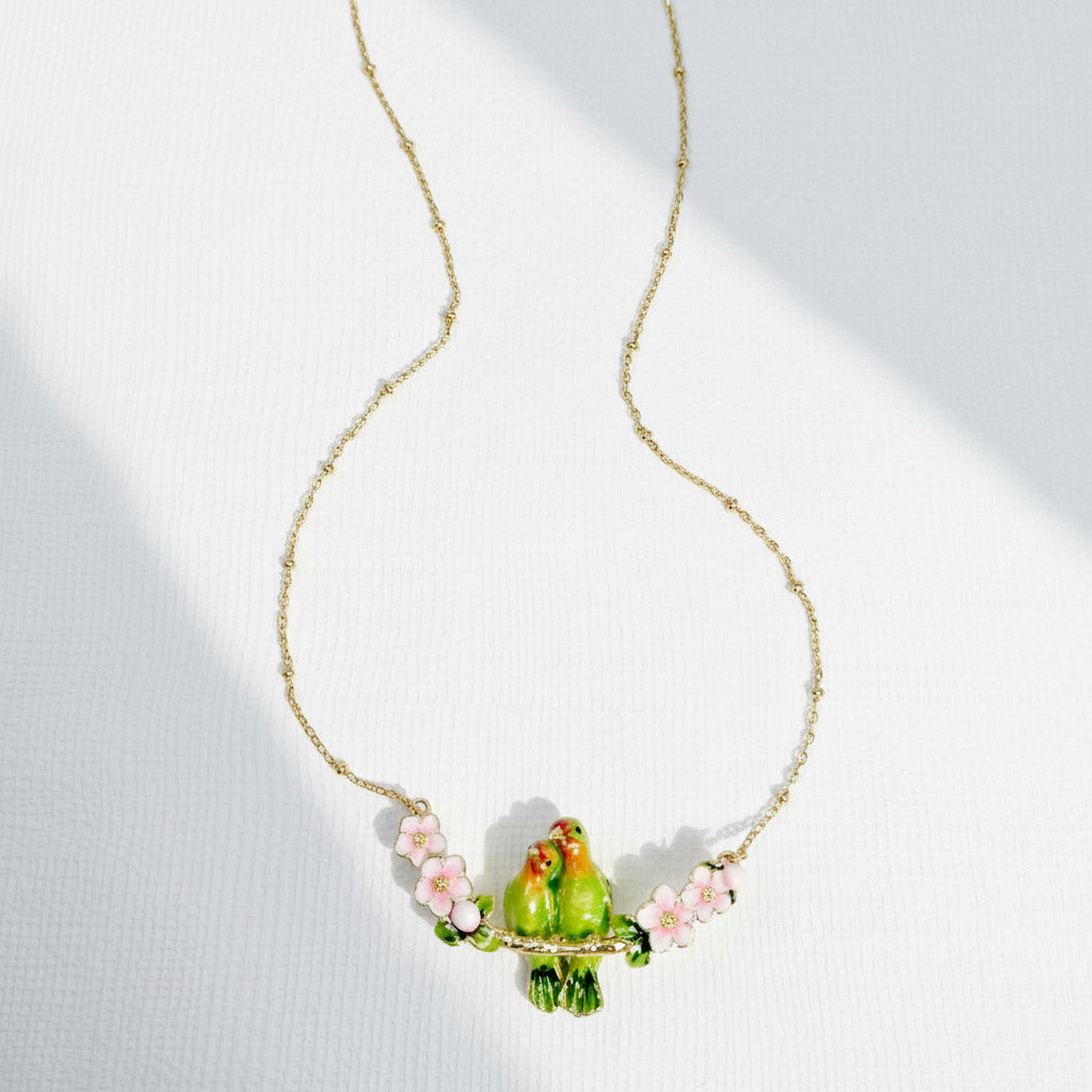 Necklace with a green parrot pendant and pink flowers on a white background