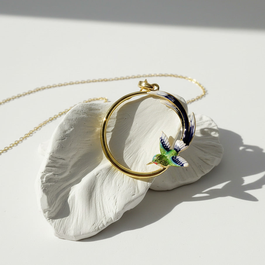 Necklace with a round pendant featuring a colorful bird design, displayed on a white shell against a light background.