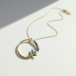 Gold necklace with a circular pendant featuring a bird design on a white background
