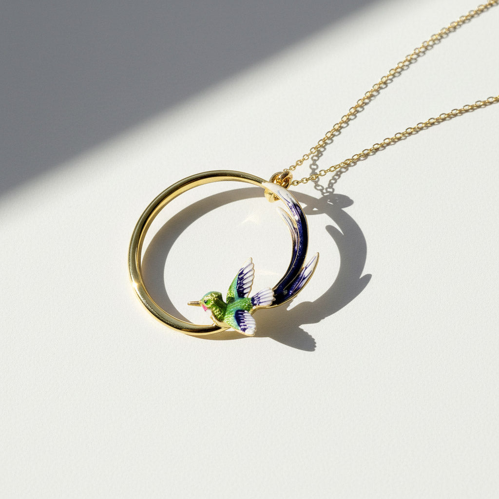 Gold necklace with a circular pendant featuring a bird design on a white background
