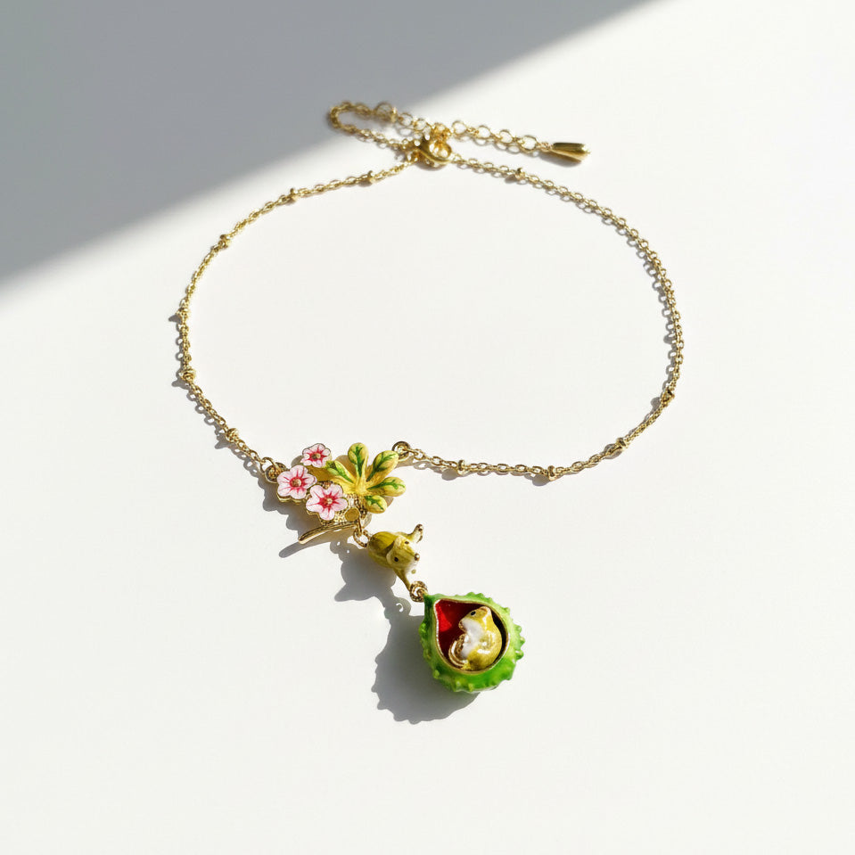 Gold bracelet with green and pink floral charms on a white background