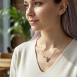 Woman wearing a delicate necklace with small pendants in an outdoor setting
