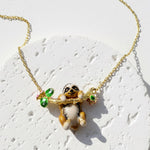 Gold necklace with a sloth pendant on a light background