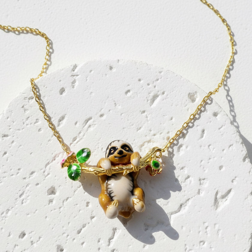 Gold necklace with a sloth pendant on a light background