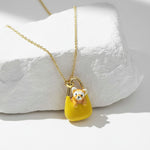 Necklace with a pendant of a dog in a yellow bag on a white stone surface