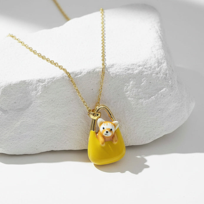 Necklace with a pendant of a dog in a yellow bag on a white stone surface