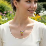 Woman wearing a necklace with a colorful pendant in a garden setting