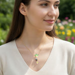 Woman wearing a gold necklace with a floral pendant in a garden setting