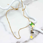 Gold-plated necklace with a handpainted enamel panda pendant hanging over a white marble background.