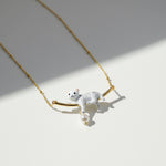 Necklace with a white cat pendant on a gold chain against a light background