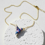 Necklace with a colorful bird pendant on a textured white surface