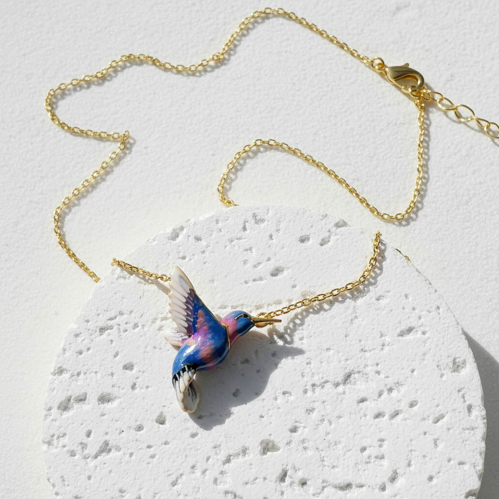 Necklace with a colorful bird pendant on a textured white surface