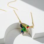 Colorful bird-shaped pendant on a gold chain against a white background
