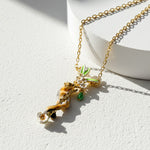 Gold necklace with a leaf-shaped pendant on a white background