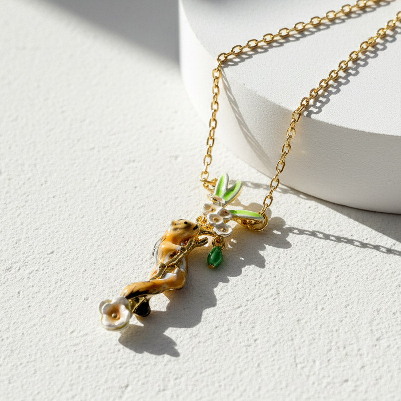 Gold necklace with a leaf-shaped pendant on a white background
