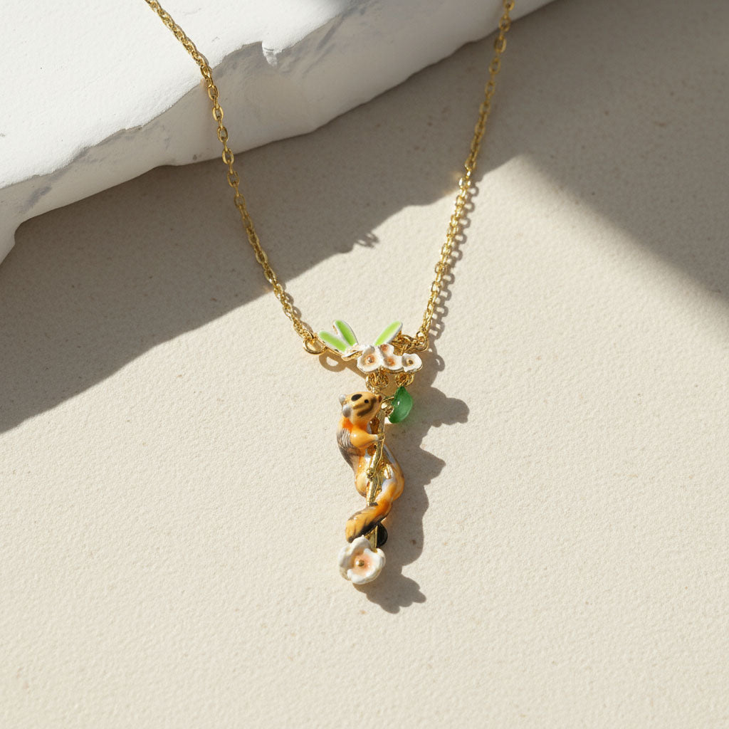 Gold necklace featuring a hand-painted chipmunk and floral vine pendant with green leaves and white flowers