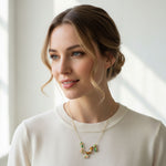 Woman wearing a necklace with a white sweater against a neutral background