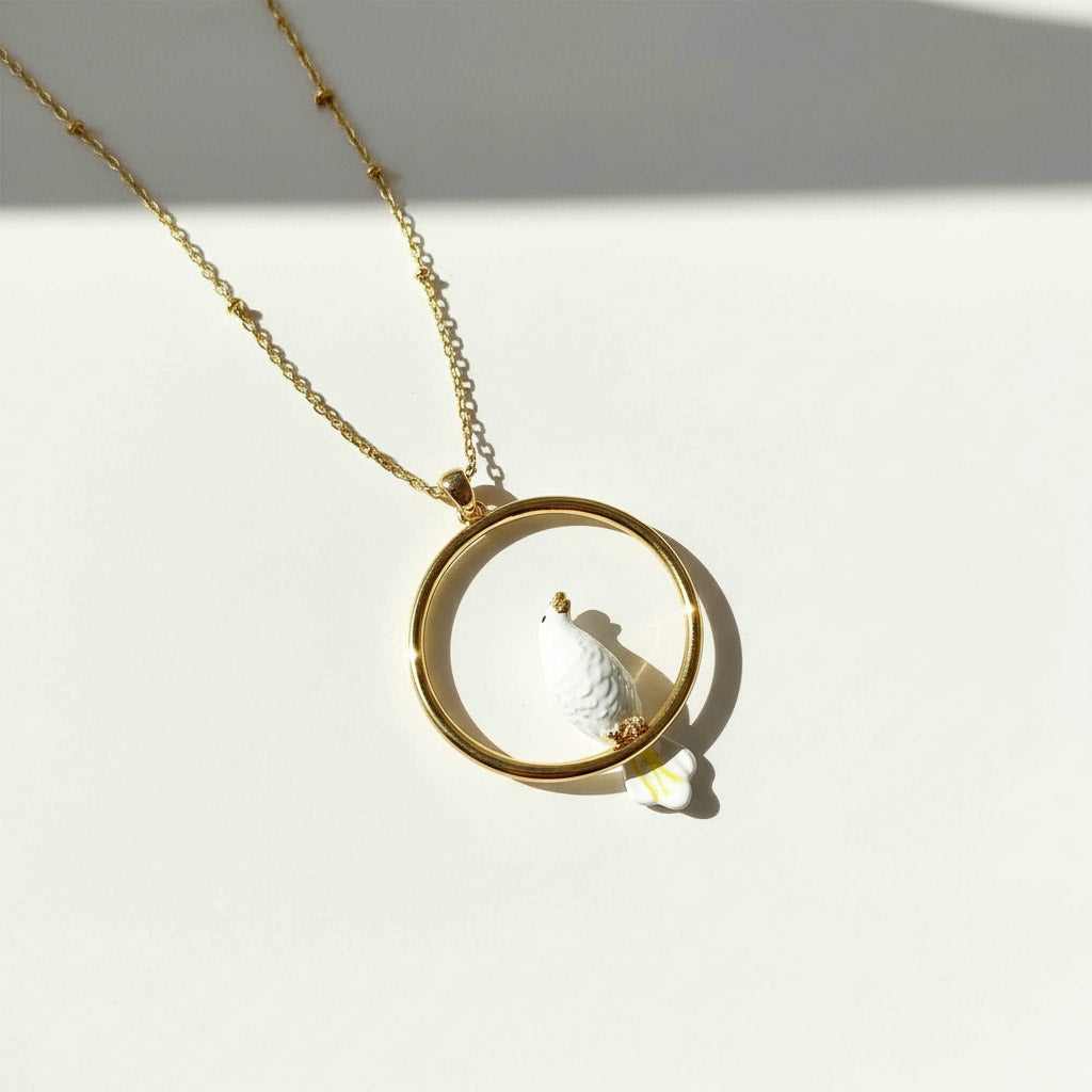 Gold necklace with a round pendant on a white background