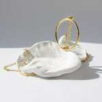 White shell with gold chain on a light gray background