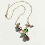 Gold necklace with floral and berry pendant on a white background