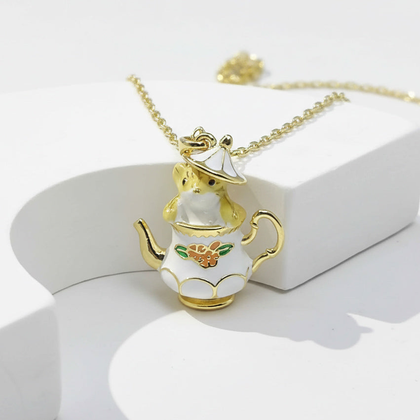 Gold and white teapot-shaped pendant on a chain against a white background